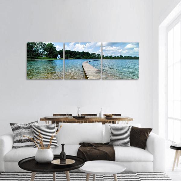 Blue Lake with Curved Wooden Boardwalk Panoramic Canvas Wall Art in white, green and blue, hung on a wall