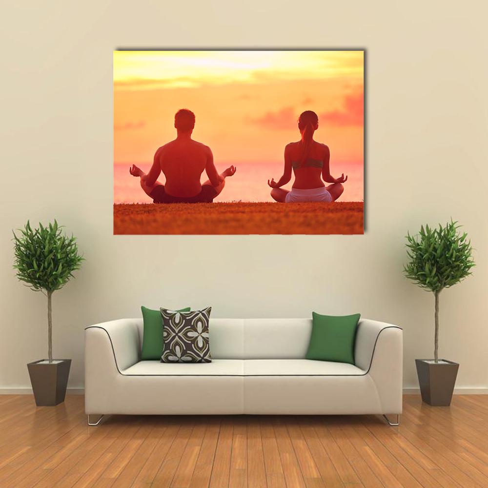 Meditating Couple at Sunset Canvas Wall Art in orange, yellow and pink, single panel hung on a wall