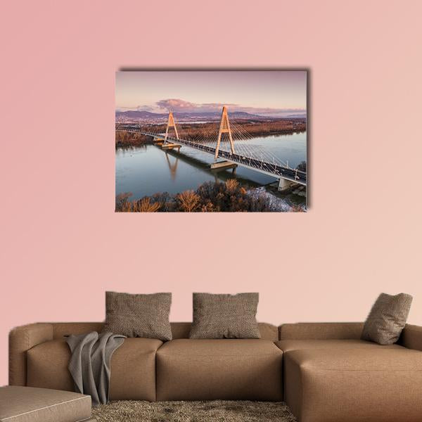 Megyeri Bridge at Sunset Over Danube River Canvas Wall Art in orange, blue and purple, single panel hung on a wall