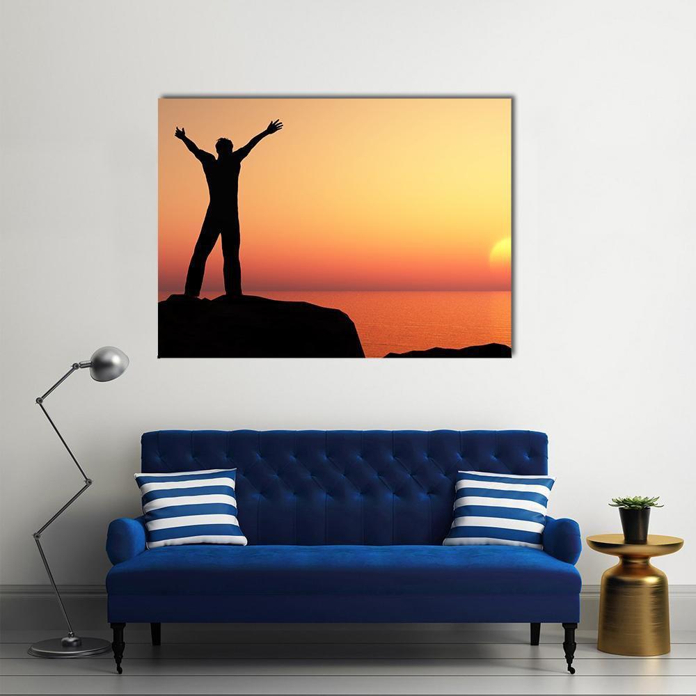 Man Greeting the Sun at Sunset Canvas Wall Art in black, orange and yellow, single panel hung on a wall