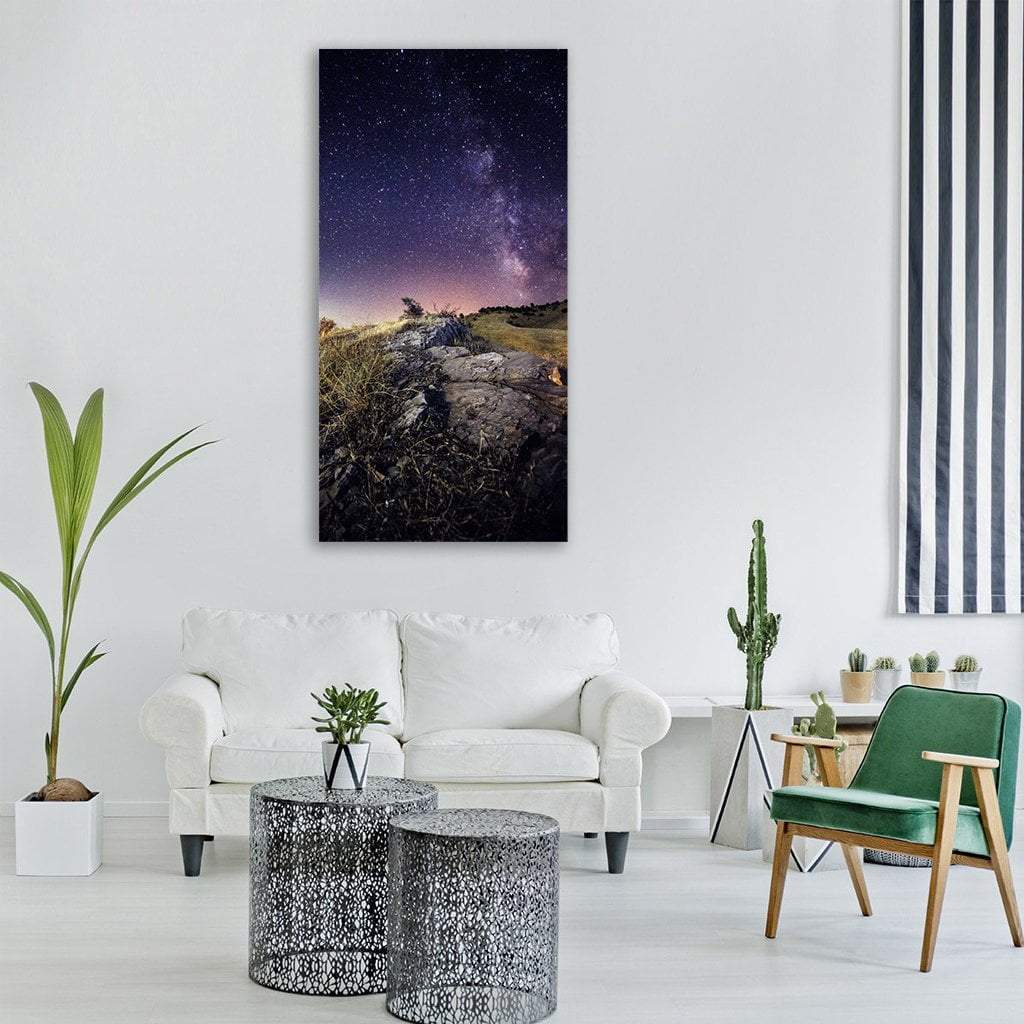 Milky Way Over Rocky Hillside Vertical Canvas Wall Art in black, blue and purple, single vertical panel hung on a wall