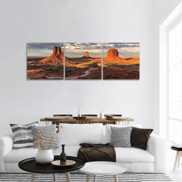 Monument Valley Sandstone Buttes at Sunset Panoramic Canvas Wall Art in brown, orange and blue, hung on a wall