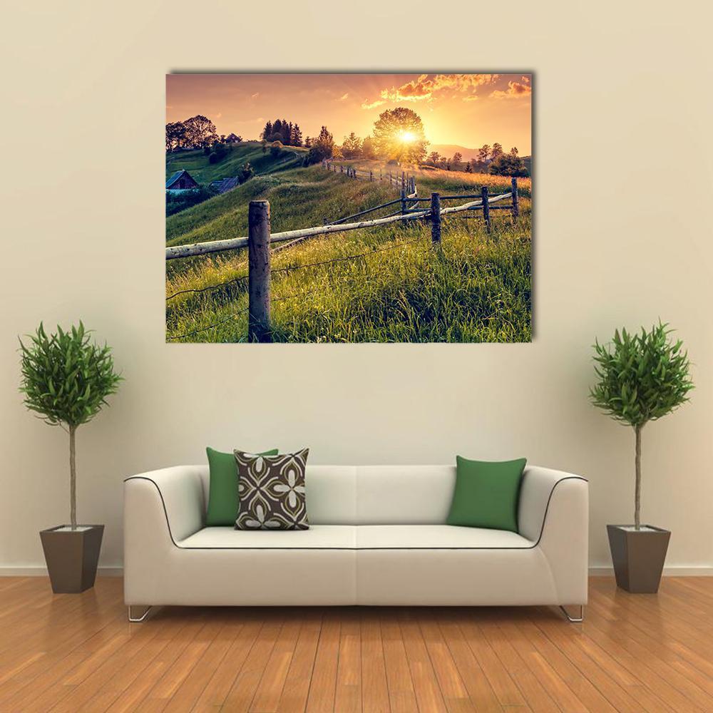 Sunset Farmhouse with Wooden Fence Canvas Wall Art in orange, yellow and green, single panel hung on a wall