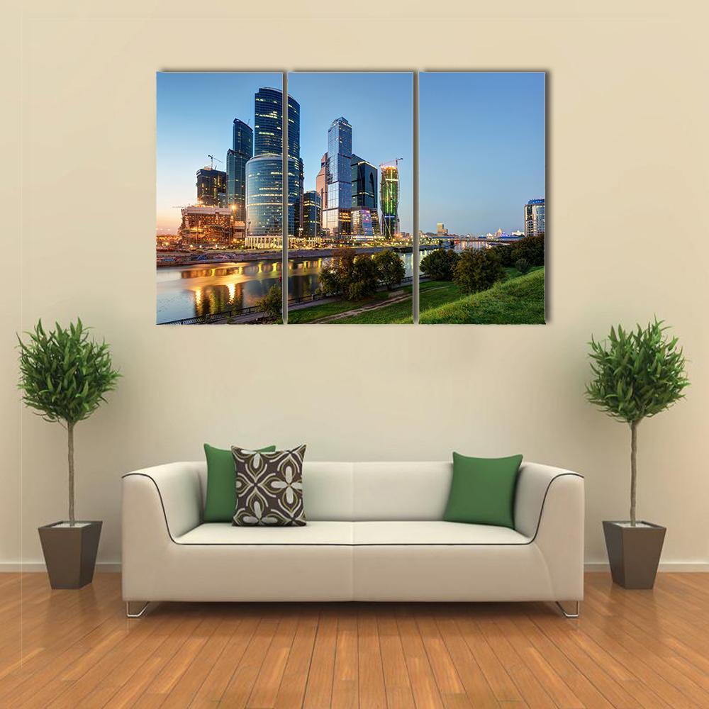 Moscow Business Center Dusk Skyline Canvas Wall Art in yellow, green and blue, 3 panel horizontal set hung on a wall