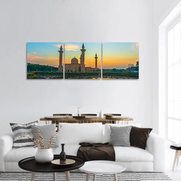 Mosque Reflection at Sunset Panoramic Canvas Wall Art in orange, yellow and blue, hung on a wall
