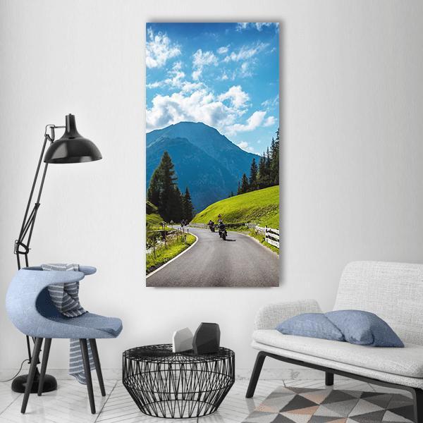 Motorcycle Riders on Mountain Pass Vertical Canvas Wall Art in gray, green and blue, hung on a wall