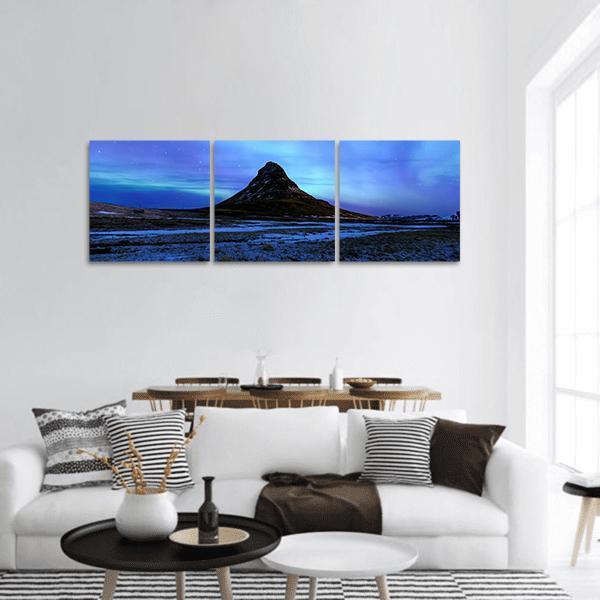 Kirkjufell Under Northern Lights Panoramic Canvas Wall Art in black, green and blue, hung on a wall
