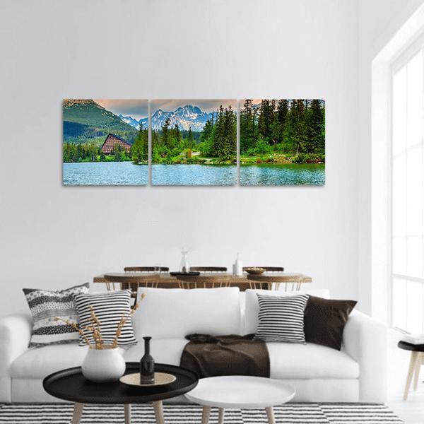 Mountain Lake with A-frame Lodge, Slovakia Panoramic Canvas Wall Art in green and blue, hung on a wall