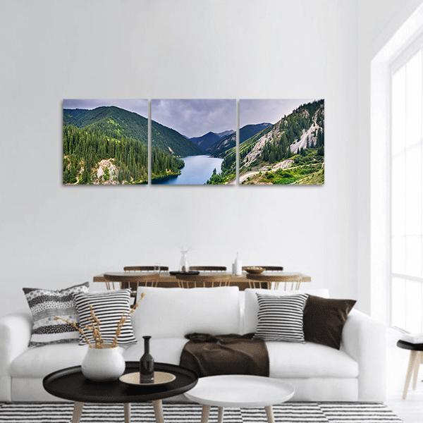 Lake Kolsai Alpine Lake and Pine Forest Panoramic Canvas Wall Art in gray, green and blue, hung on a wall
