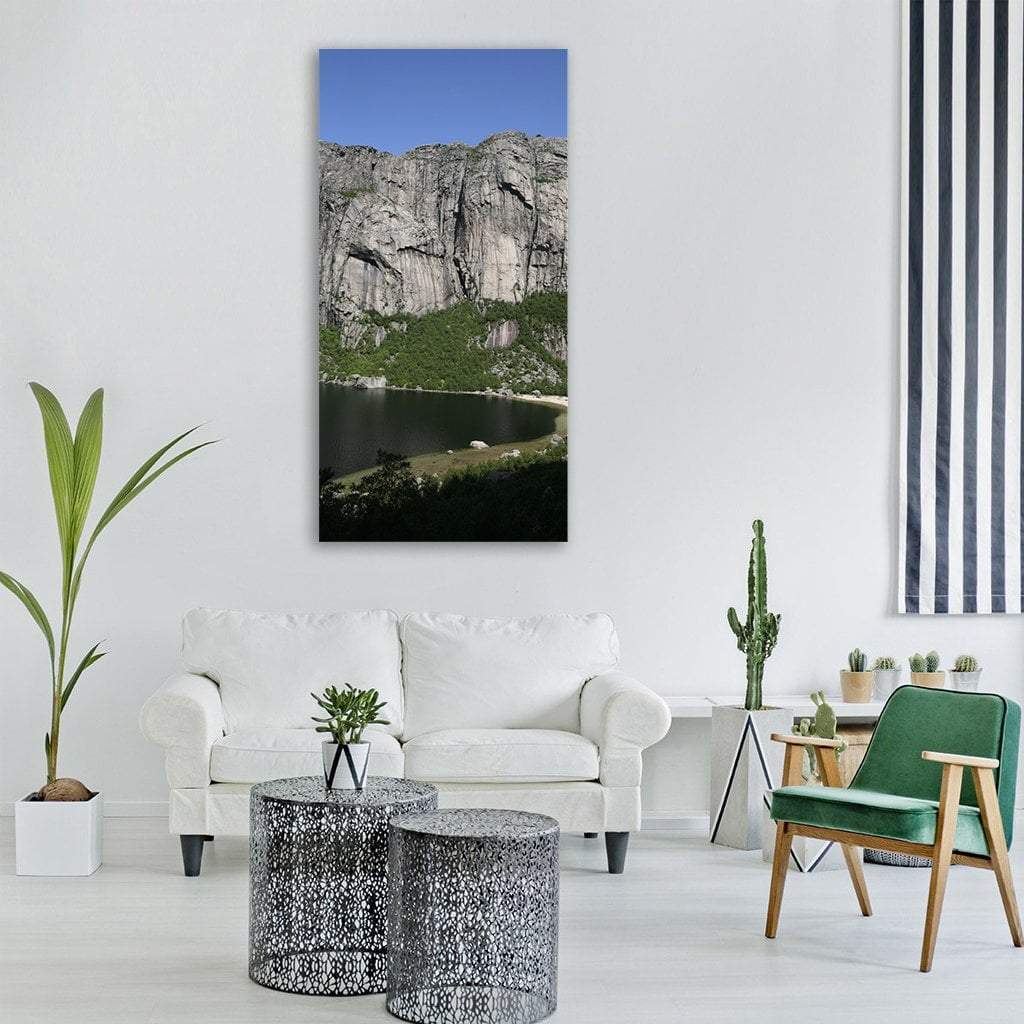 Rocky Cliff Above Mountain Lake Vertical Canvas Wall Art in gray, green and blue, single vertical panel hung on a wall
