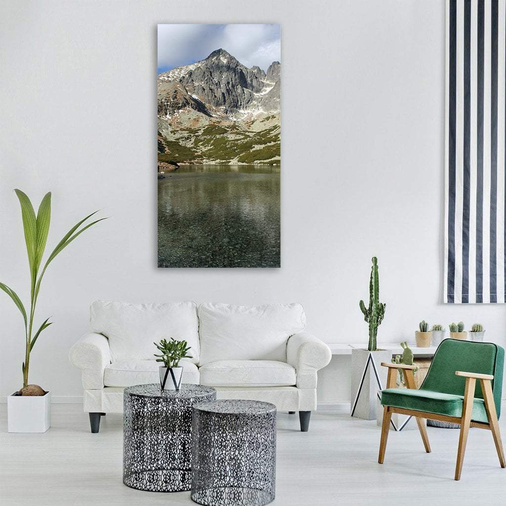 Clear Mountain Lake with Snowy Peak Vertical Canvas Wall Art in gray, green and blue, single vertical panel hung on a wall