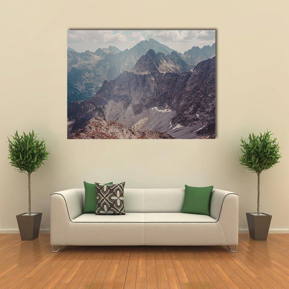 Layered Mountains with Snow Patches Canvas Wall Art in gray, brown and blue, single panel hung on a wall