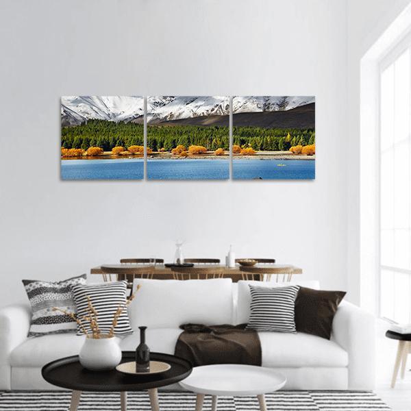 Snow-capped Mountains Over Autumn Lake Panoramic Canvas Wall Art in white, green and blue, hung on a wall