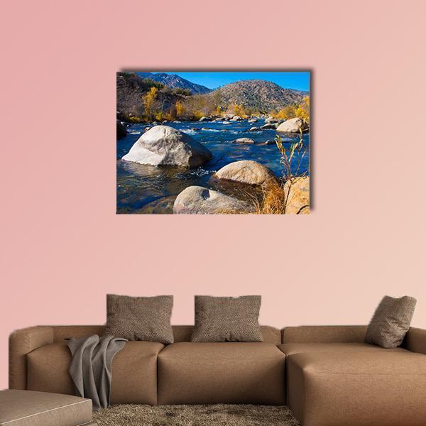 Rocky River with Autumn Foliage Canvas Wall Art in brown, yellow and blue, single panel hung on a wall