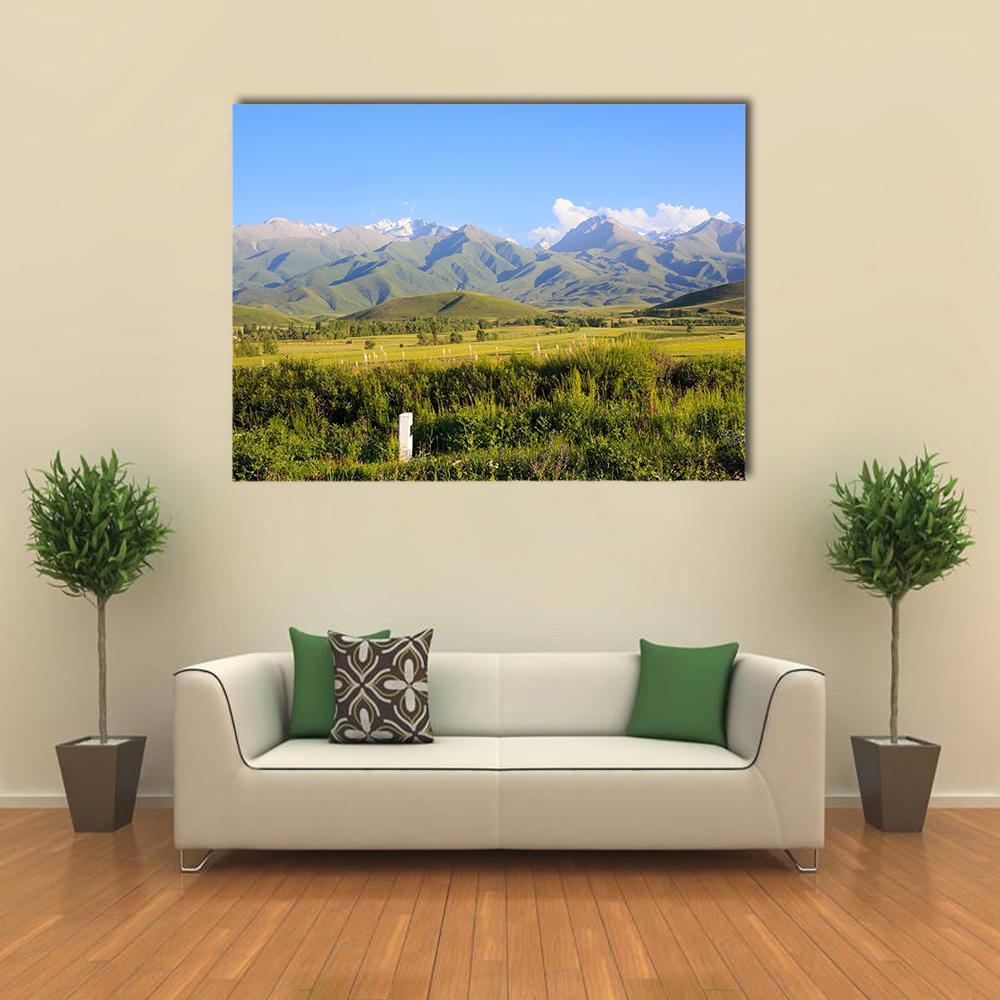 Snow-capped Mountains and Green Fields Canvas Wall Art in gray, green and blue, single panel hung on a wall