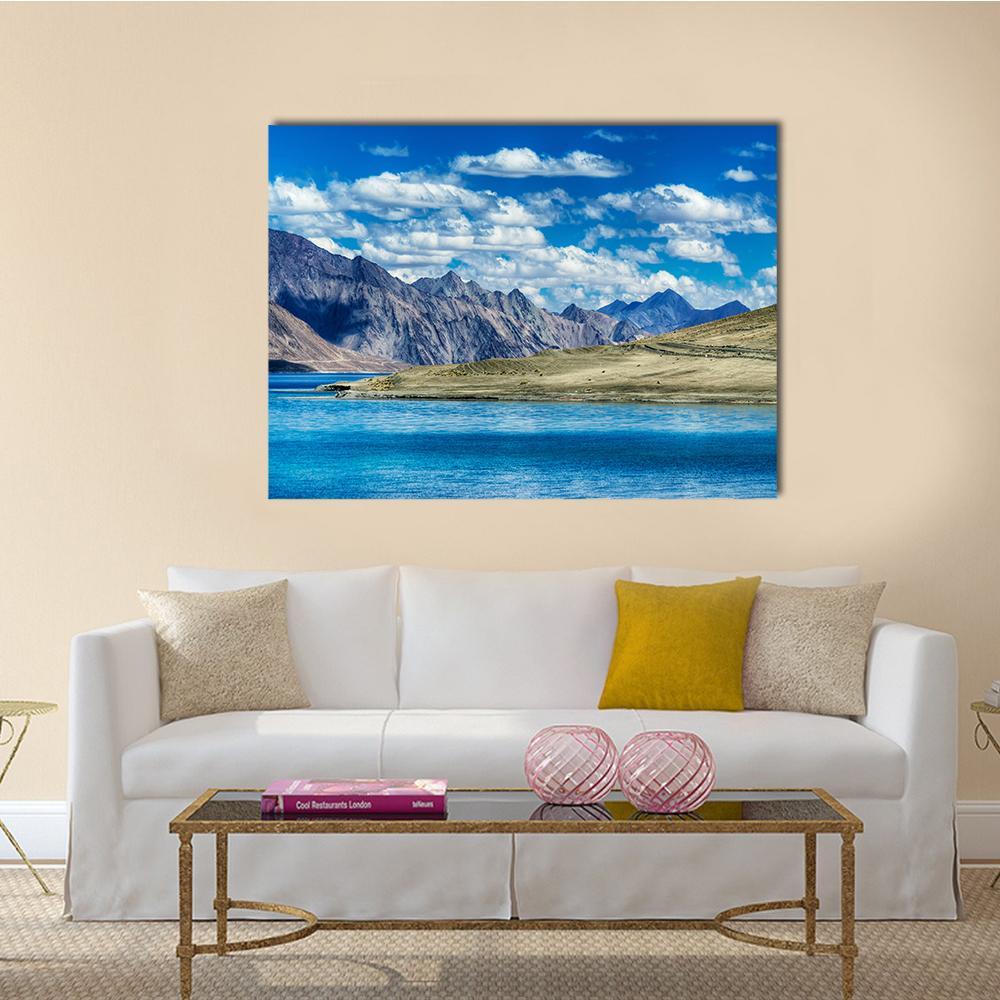 Mountain Peaks Over Vibrant Blue Lake Canvas Wall Art in white, brown and blue, single panel hung on a wall