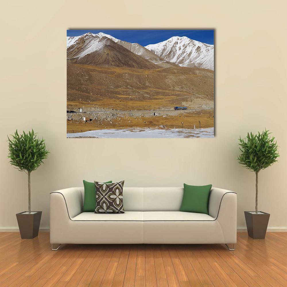 Khunjerab Pass Mountain Road with Blue Truck Canvas Wall Art in white, brown and blue, single panel hung on a wall
