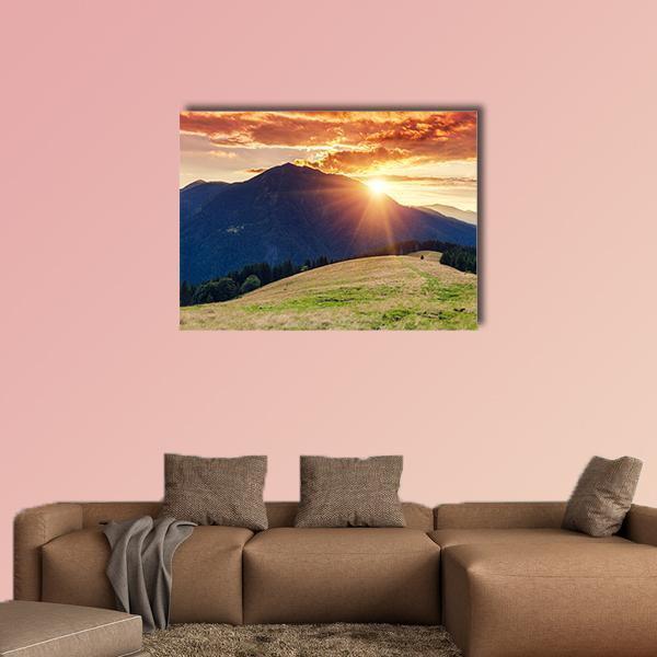 Sun Rays Behind Mountain at Sunset Canvas Wall Art in orange, green and blue, single panel hung on a wall
