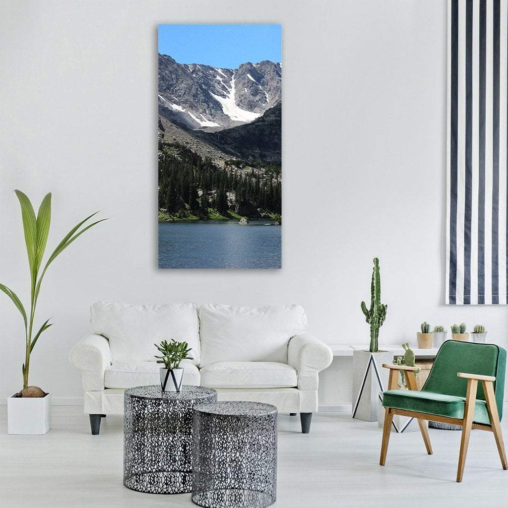 Alpine Lake with Pine Forest and Snow-capped Mountains Vertical Canvas Wall Art in gray, green and blue, single vertical panel hung on a wall