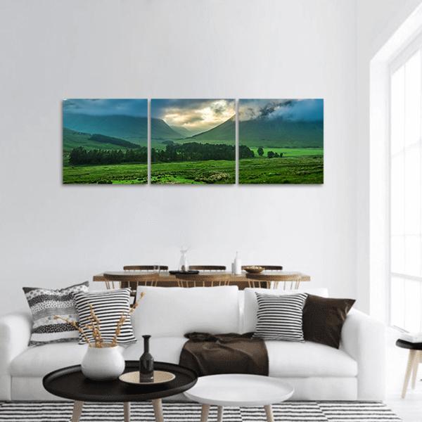 Foggy Sunset Over Rolling Green Hills Panoramic Canvas Wall Art in yellow, green and blue, hung on a wall