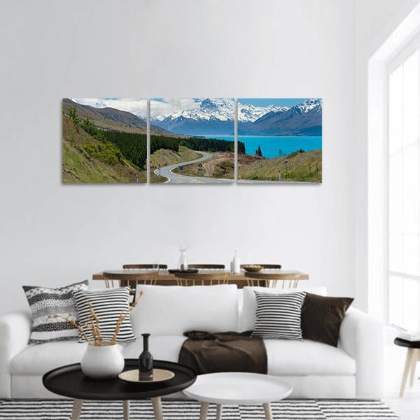 Winding Road Beside Turquoise Glacial Lake Panoramic Canvas Wall Art in white, green and blue, hung on a wall