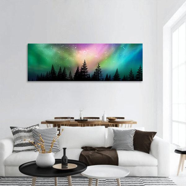 Multicolored Northern Lights Over Pine Forest Panoramic Canvas Wall Art in green, blue and pink, hung on a wall