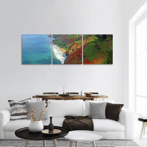 Na Pali Coast Cliffs and Shoreline Panoramic Canvas Wall Art in brown, green and blue, hung on a wall