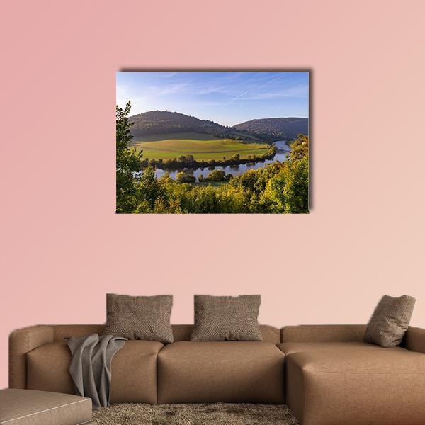 Sunrise Over River and Hills Canvas Wall Art in yellow, green and blue, single panel hung on a wall