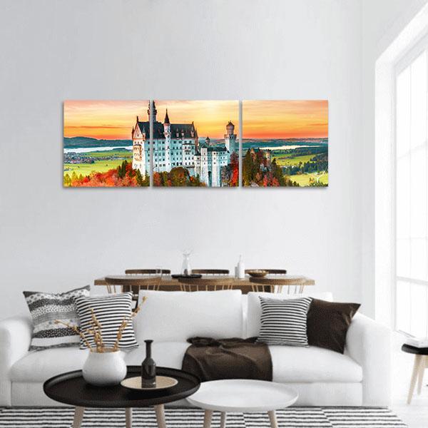 Neuschwanstein Castle in Autumn Light Panoramic Canvas Wall Art in orange, yellow and green, hung on a wall
