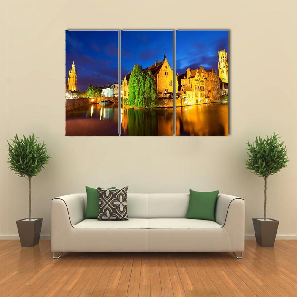Bruges Canal at Night Canvas Wall Art in orange, yellow and blue, 3 panel horizontal set hung on a wall