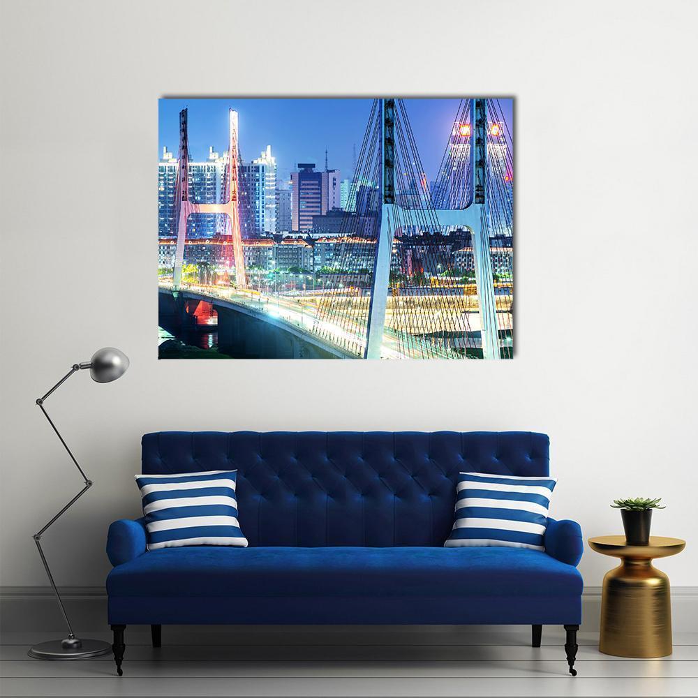 Illuminated Bridge Over Shanghai's Night Skyline Canvas Wall Art in white, yellow and blue, single panel hung on a wall