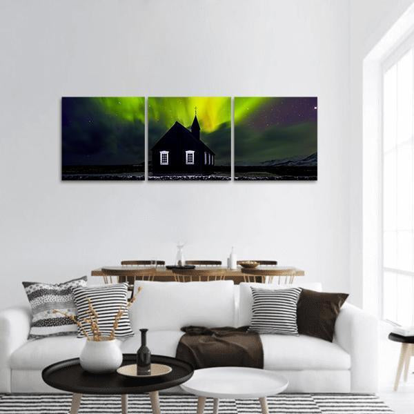 Green Northern Lights Over Church Panoramic Canvas Wall Art in black, yellow and green, single panel hung on a wall