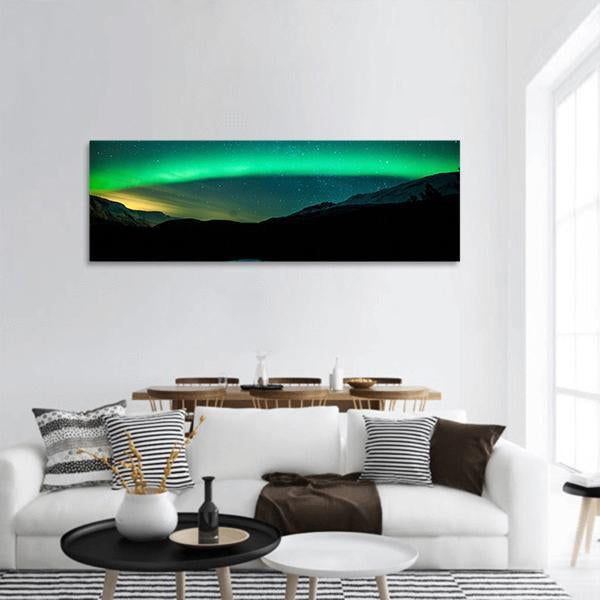 Northern Lights Arc Panoramic Canvas Wall Art in black, green and blue, hung on a wall