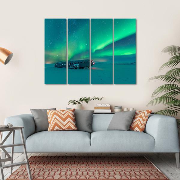 Northern Lights Over Plane Wreck Canvas Wall Art in green and blue, hung on a wall