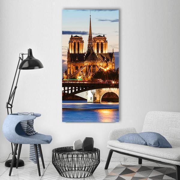 Notre-dame Cathedral at Twilight Vertical Canvas Wall Art in gold, orange and blue, hung on a wall