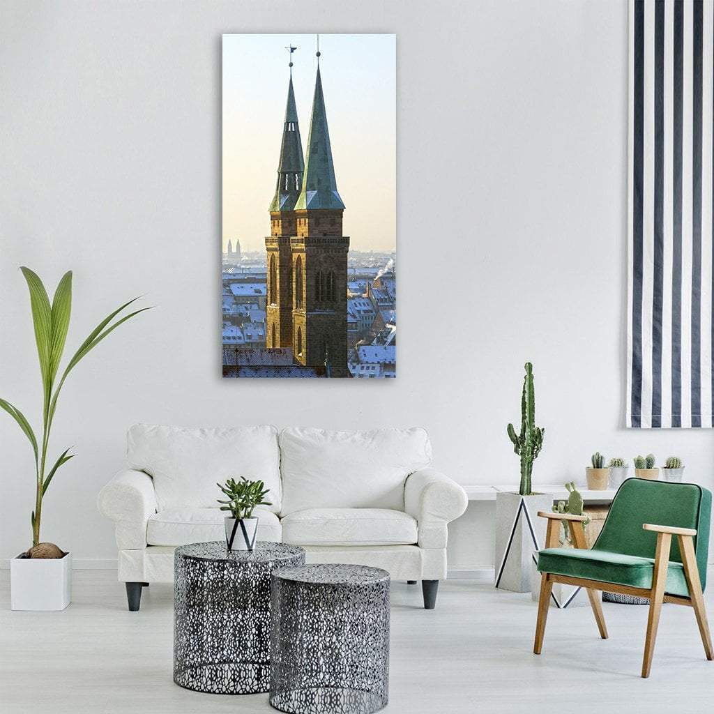 Gothic Twin Towers Over Snowy Cityscape Vertical Canvas Wall Art in gray, brown and blue, single vertical panel hung on a wall