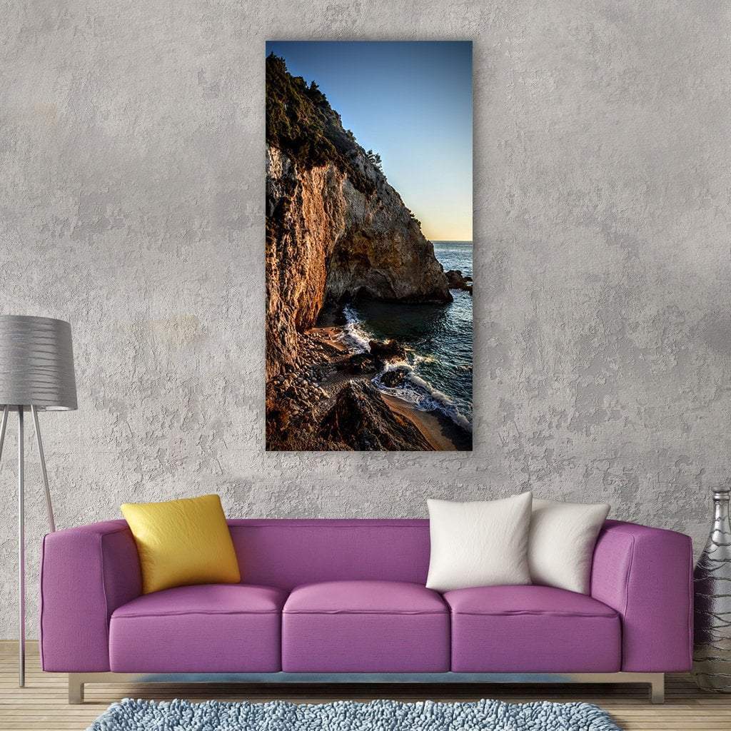 Sunlit Waves Near Sea Rocks Vertical Canvas Wall Art in brown, orange and blue, single vertical panel hung on a wall