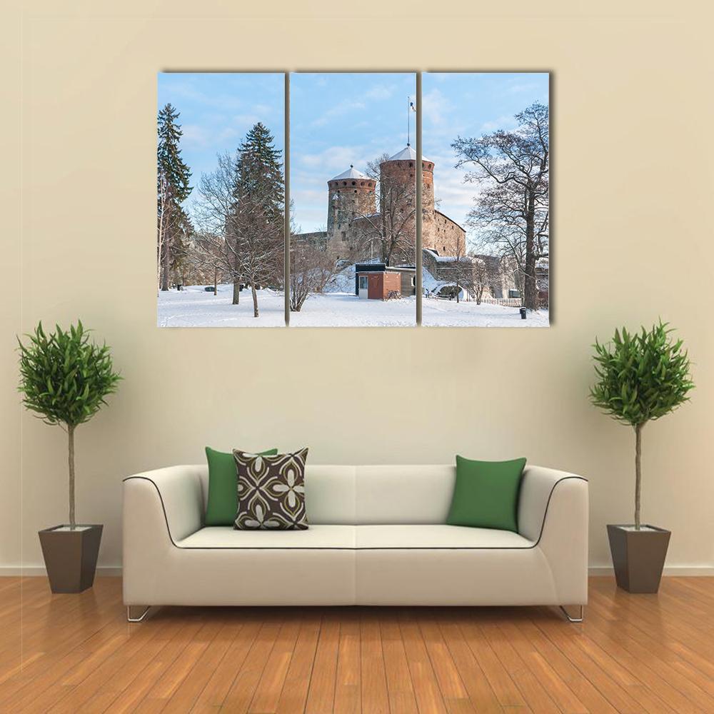 Olavinlinna Castle in Winter Canvas Wall Art in white, brown and blue, 3 panel horizontal set hung on a wall