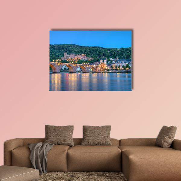 Illuminated Castle and Stone Arch Bridge Canvas Wall Art in brown, gold and blue, single panel hung on a wall