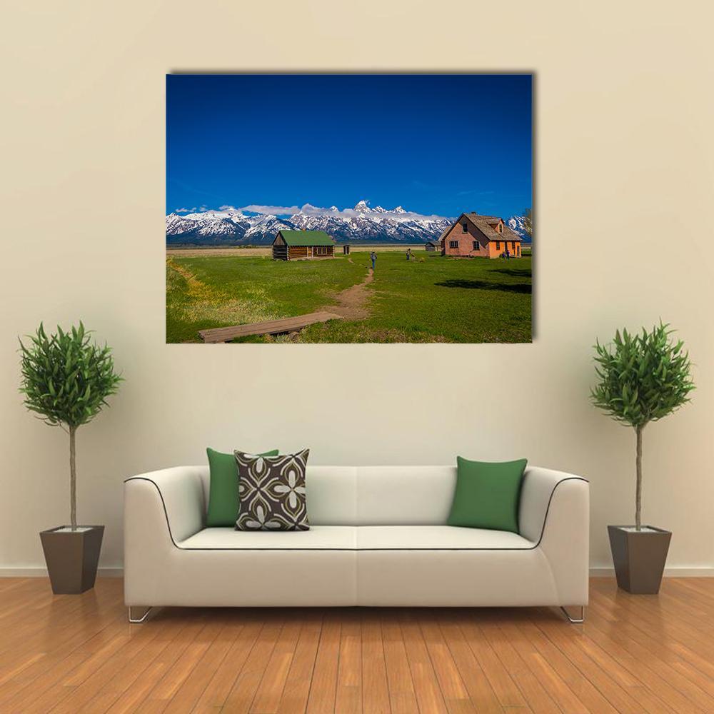 Old Mormon Barn by Snow-capped Mountains Canvas Wall Art in brown, green and blue, single panel hung on a wall