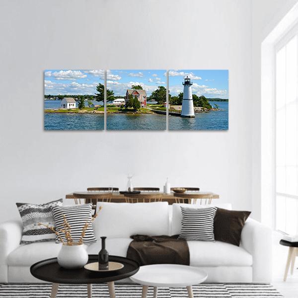 White Lighthouse on Coastal Island Panoramic Canvas Wall Art in white, green and blue, hung on a wall