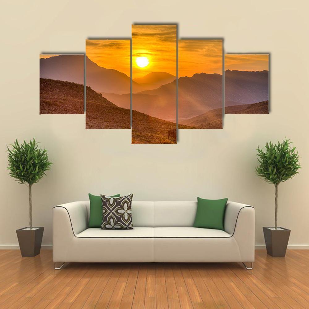 Orange Sunset Over Mountains Canvas Wall Art in brown, orange and yellow, 5 panel Star layout hung on a wall