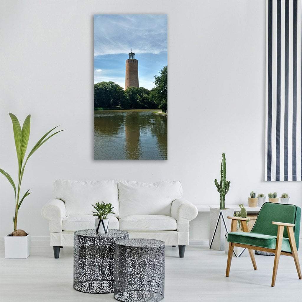 Brick Lighthouse with Pond Reflection Vertical Canvas Wall Art in brown, green and blue, single vertical panel hung on a wall