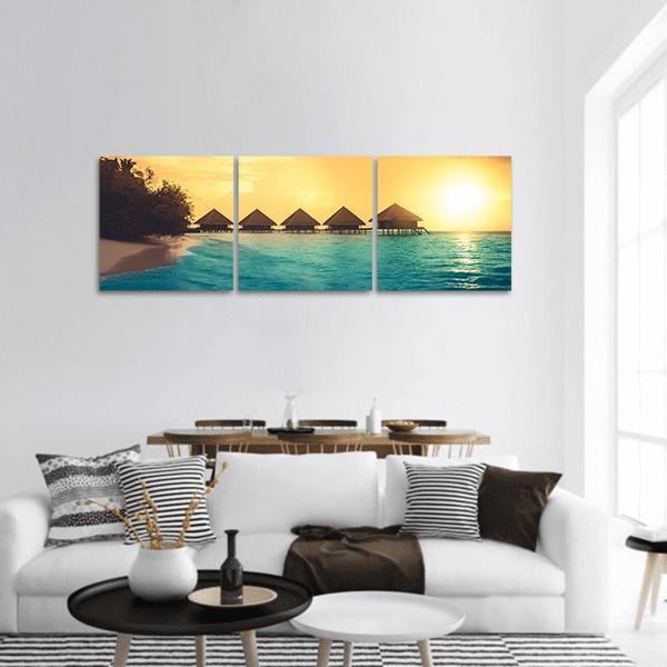 Overwater Bungalows in Maldives at Sunset Panoramic Canvas Wall Art in orange, yellow and blue, hung on a wall