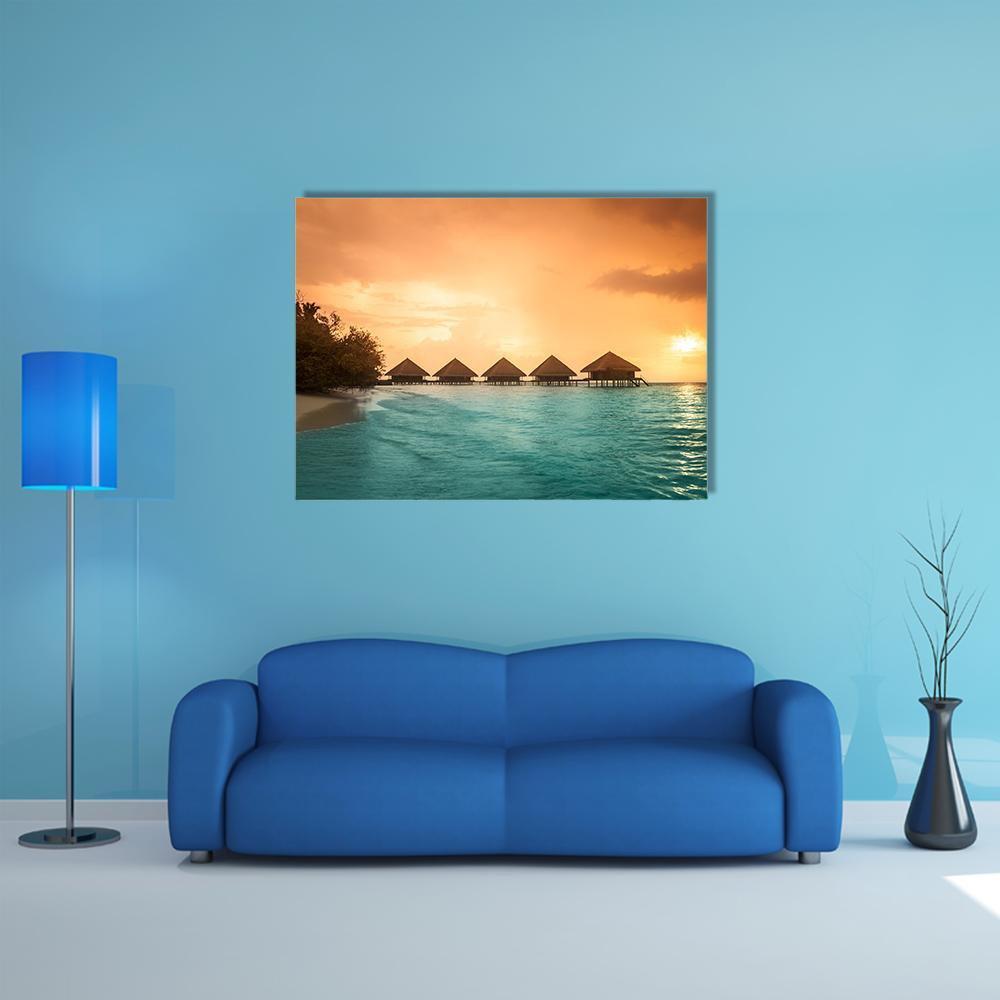 Overwater Bungalows at Sunset Canvas Wall Art in orange, yellow and blue, single panel hung on a wall
