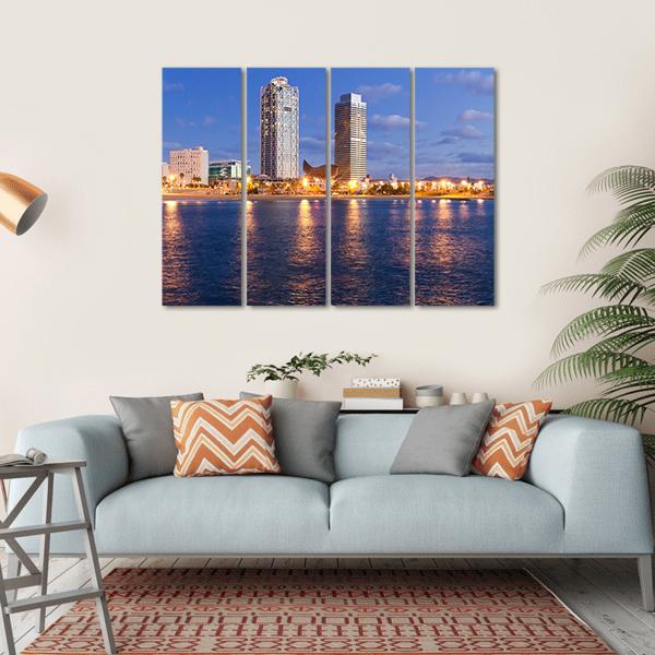 Barcelona Skyline at Twilight Canvas Wall Art in yellow, blue and navy, hung on a wall