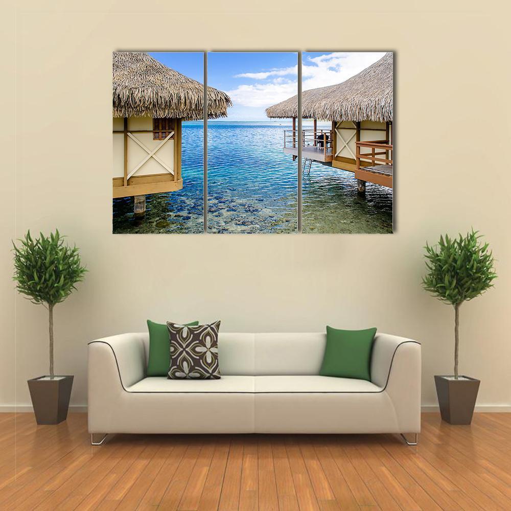 Overwater Bungalows in Tropical Paradise Canvas Wall Art in beige, brown and blue, 3 panel horizontal set hung on a wall