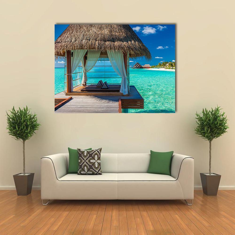 Tropical Lagoon View with Overwater Bungalow Canvas Wall Art in brown and blue, single panel hung on a wall