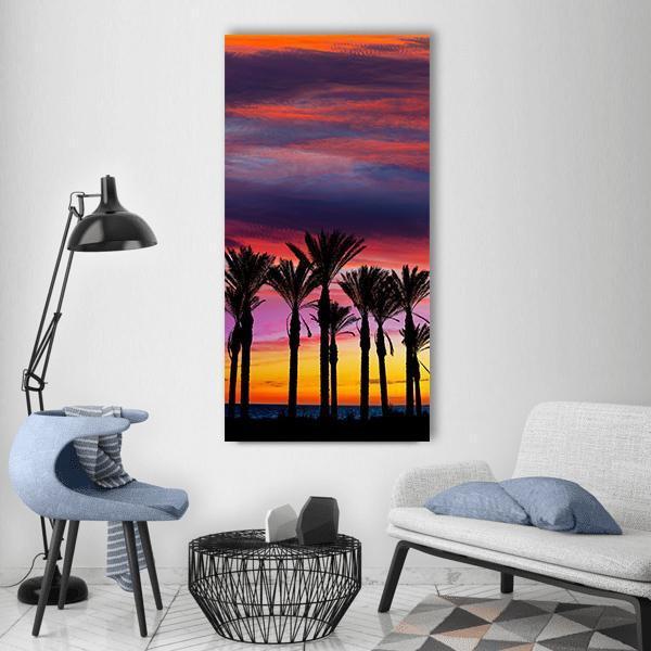 Retamar Beach Palm Silhouettes at Sunset Vertical Canvas Wall Art in black, orange and purple, single vertical panel hung on a wall
