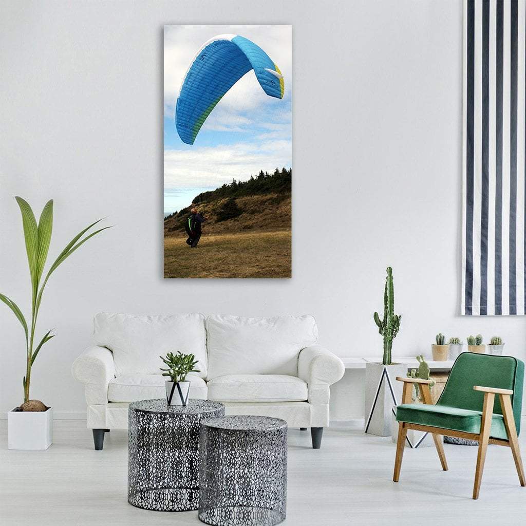 Paraglider Over Grassy Mountain Vertical Canvas Wall Art in white, brown and blue, single vertical panel hung on a wall